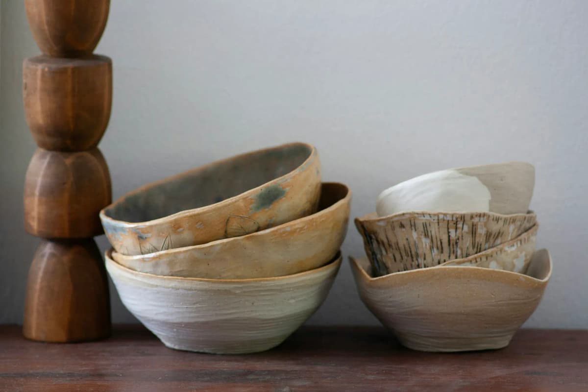 Stacked handmade ceramic bowls on a wooden shelf