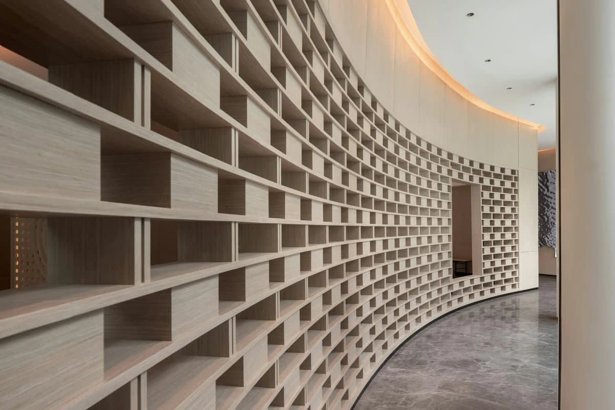 A curved wall of pale timber shelves under indirect light