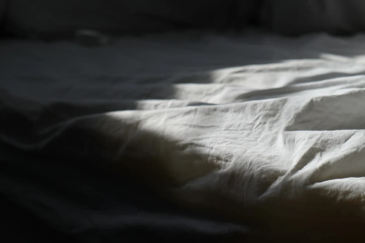 Rumpled linen on a bed in low light