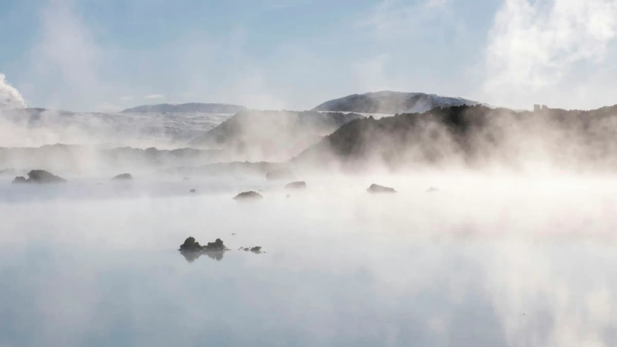 Steam drifting over still water at dawn