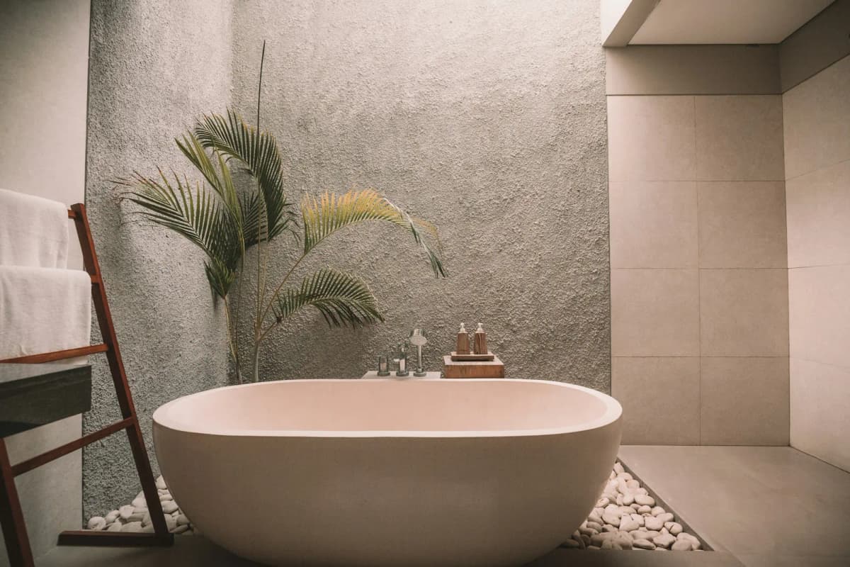 A freestanding stone bath against a textured wall