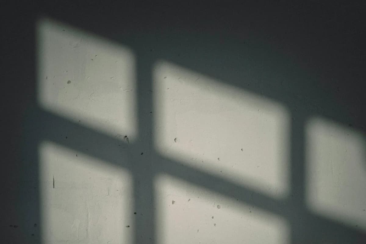 A window’s shadow on a dim plaster wall